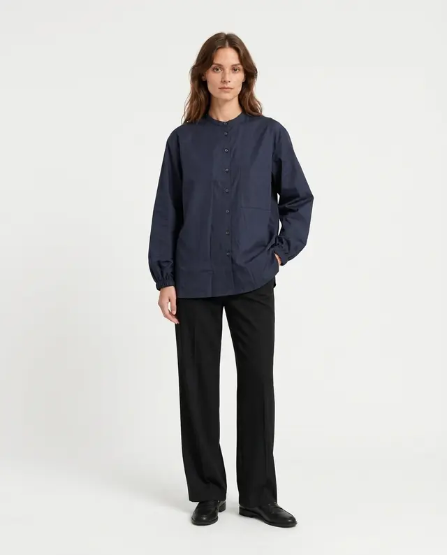 A model in a navy shirt and black trousers in a studio